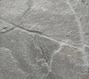 Close-up of gray stone paving with light mortar joints forming curved lines.