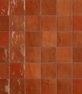 Close-up of red ceramic tiles arranged in a grid; the leftmost column shows worn, scuffed glaze.