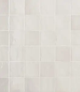 Close-up of a pale beige ceramic tile wall, tiles arranged in a grid with subtle marbling.