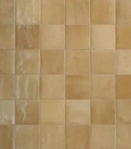 Close-up of a beige ceramic tile wall with a grid of square tiles and light grout lines.