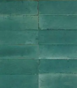 Close-up of teal-green rectangular tiles with visible grout lines on a wall.