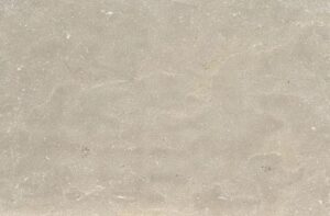 Close-up of a light beige concrete surface with subtle scratches and stains.