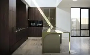 Modern kitchen with dark wood cabinets, marble island, and large glass doors letting sunlight in.