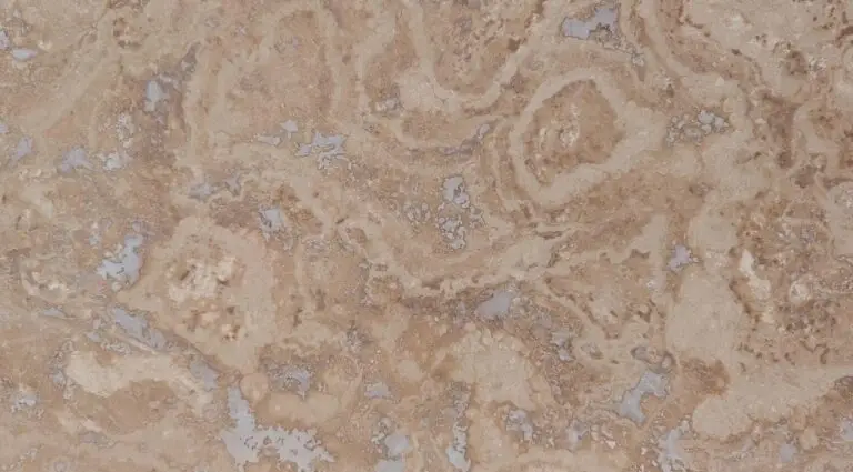Close-up of a beige, weathered rock surface with brown and gray patches and swirled patterns.